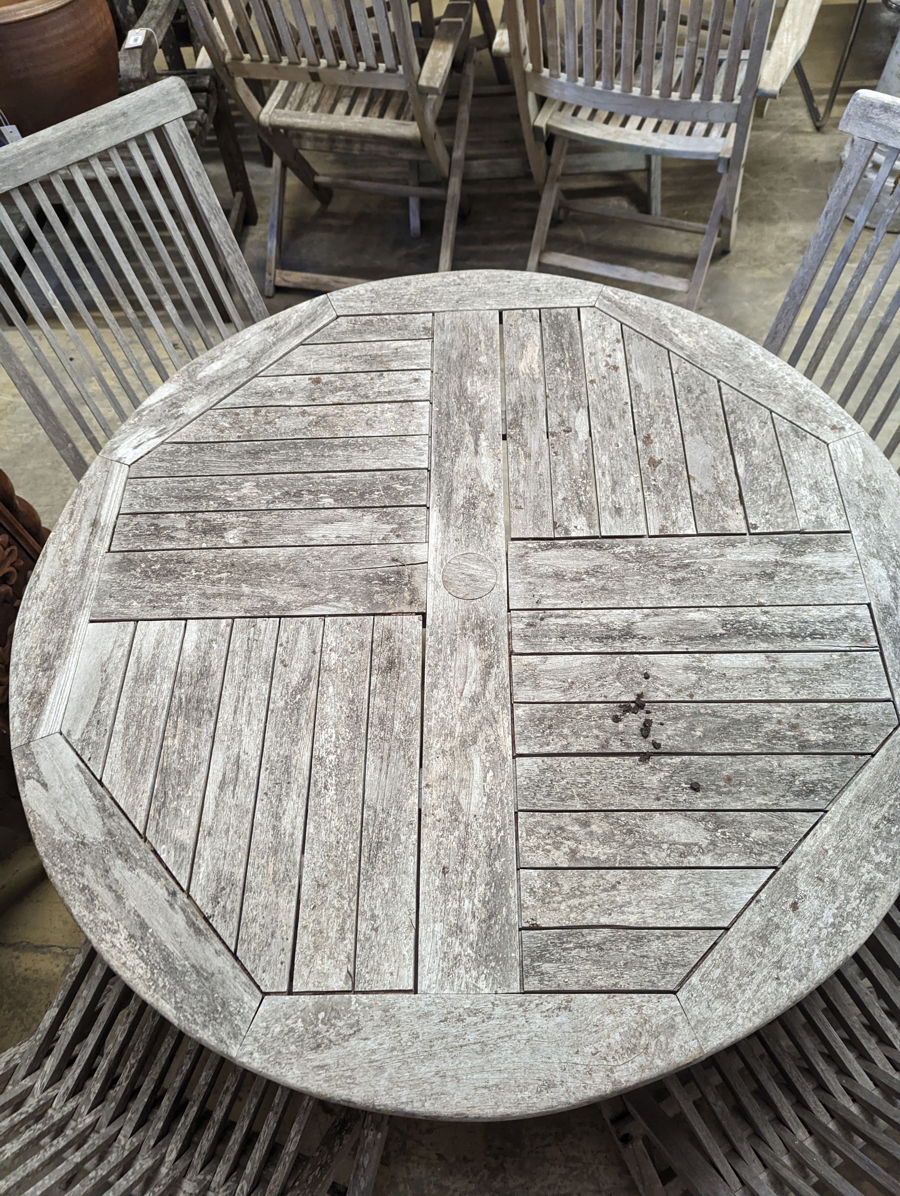 A circular weathered teak garden table, diameter 100cm, height 75cm together with four folding chairs